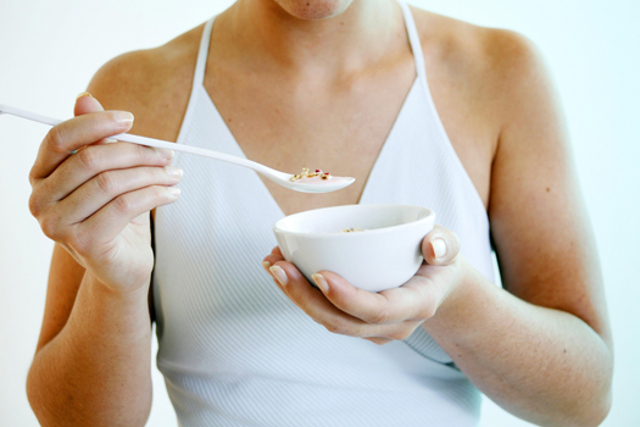 Young woman holds a bowl of cereals.