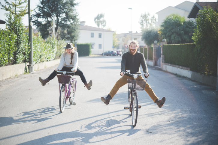Young couple cycling with legs out