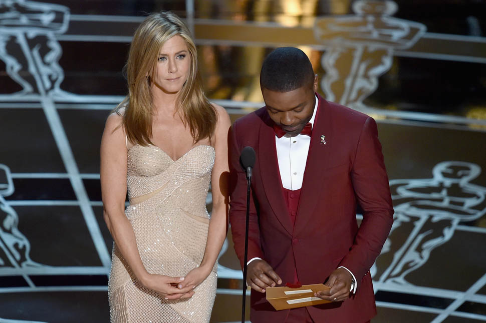 HOLLYWOOD, CA - FEBRUARY 22:  Actress Jennifer Aniston and actor David Oyelowo speak onstage during the 87th Annual Academy Awards at Dolby Theatre on February 22, 2015 in Hollywood, California.  (Photo by Kevin Winter/Getty Images)