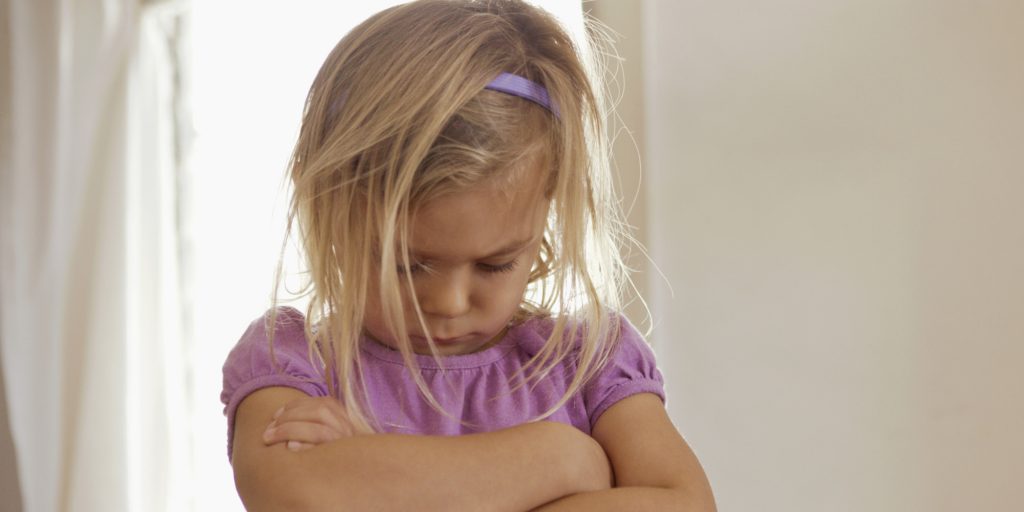Young girl with head down and arms folded having tantrum