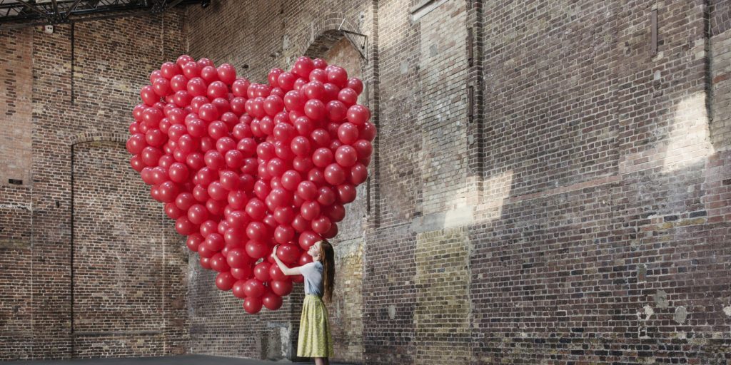 Woman in warehouse with heart made of balloons