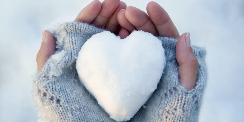 Woman holding heart-shaped snowball, close-up of hands